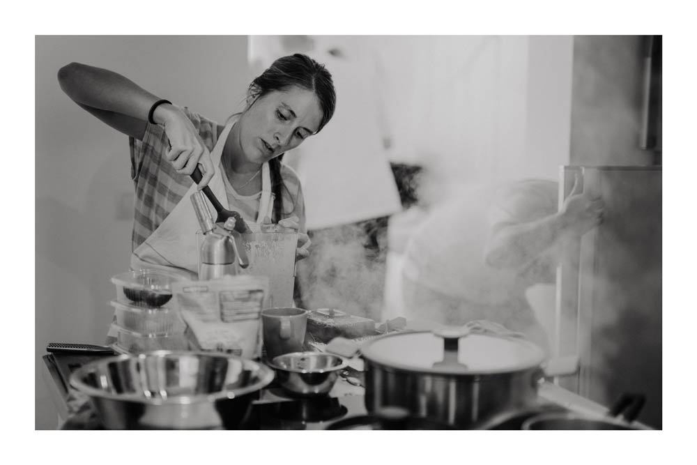 Female chef mixing ingredients behind a steaming stove